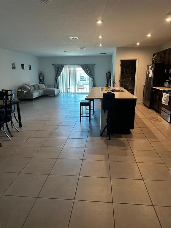 An open-concept living area features tile flooring, a kitchen island, and a sliding glass door — 4762 VELLACITO WAY, DAVENPORT, FL