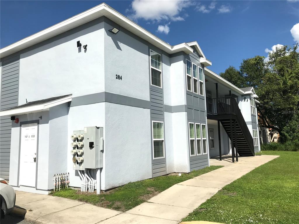 A two-story apartment building exterior with light blue stucco walls and a metal staircase — 284 GARDNER LANE UNIT A, KISSIMMEE, FL