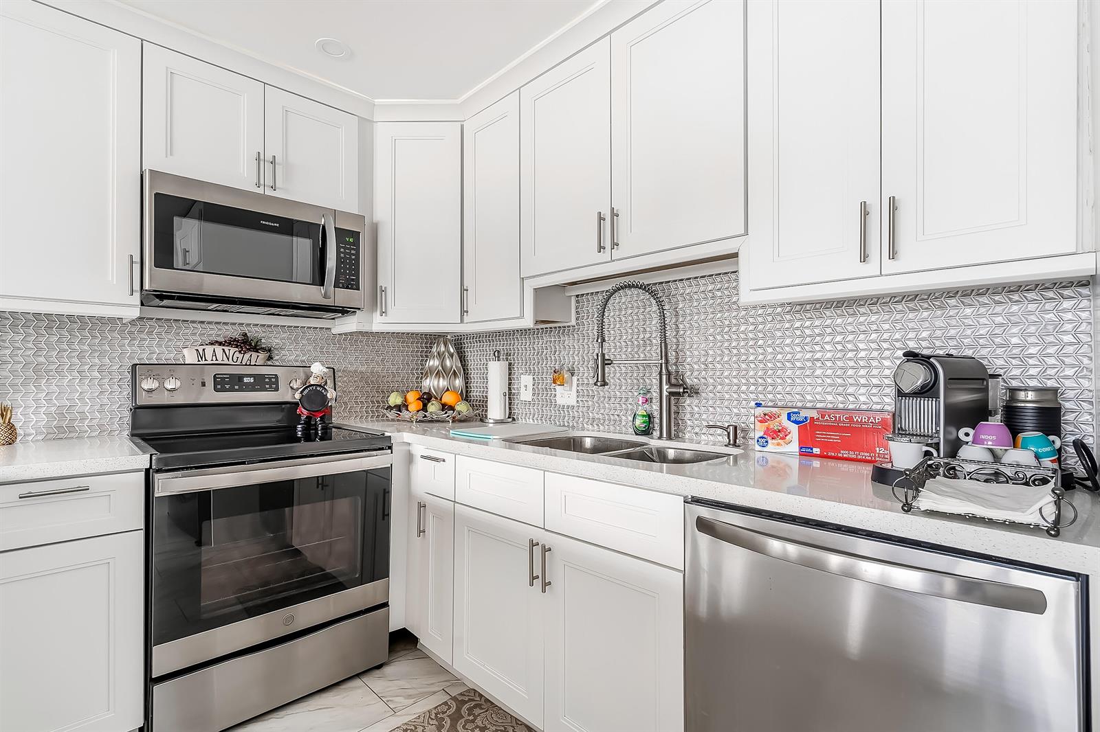A kitchen with white cabinets, stainless steel appliances, and a gray patterned tile backsplash — 1012 Lincoln # 1012, Boca Raton FL 33434, BOCA RATON, FL