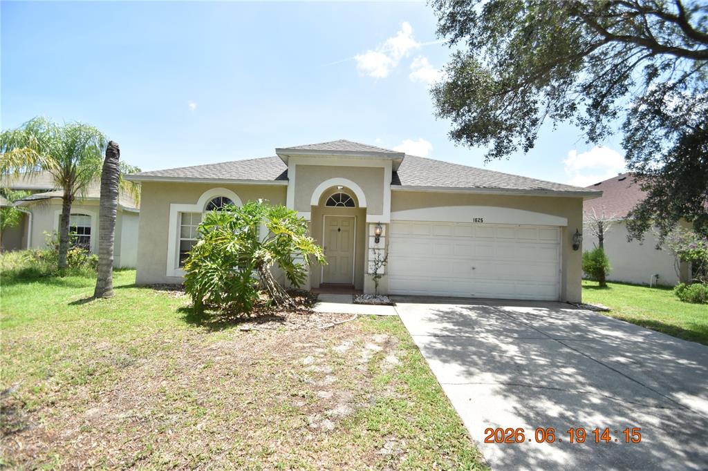 A single-story beige house with a two-car garage and a front yard with landscaping — 1625 OPEN FIELD LOOP, BRANDON, FL