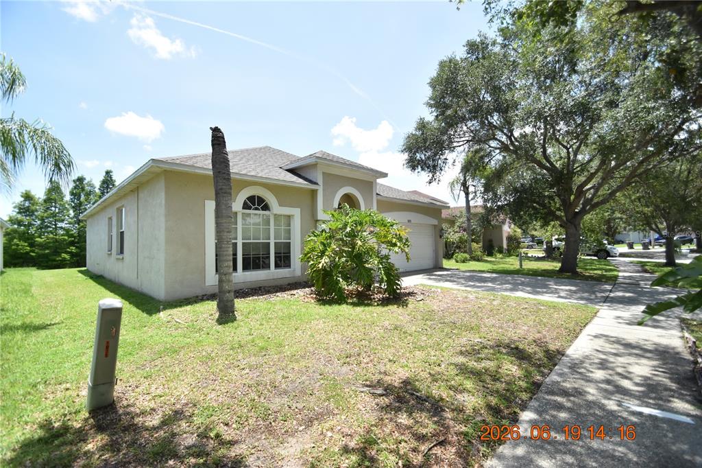 A single-story house with a beige stucco exterior, a two-car garage, and a front lawn — 1625 OPEN FIELD LOOP, BRANDON, FL