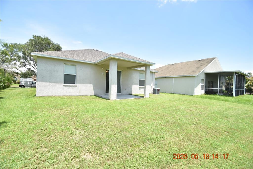 The rear exterior of a single-story house features a covered patio and a grassy yard — 1625 OPEN FIELD LOOP, BRANDON, FL