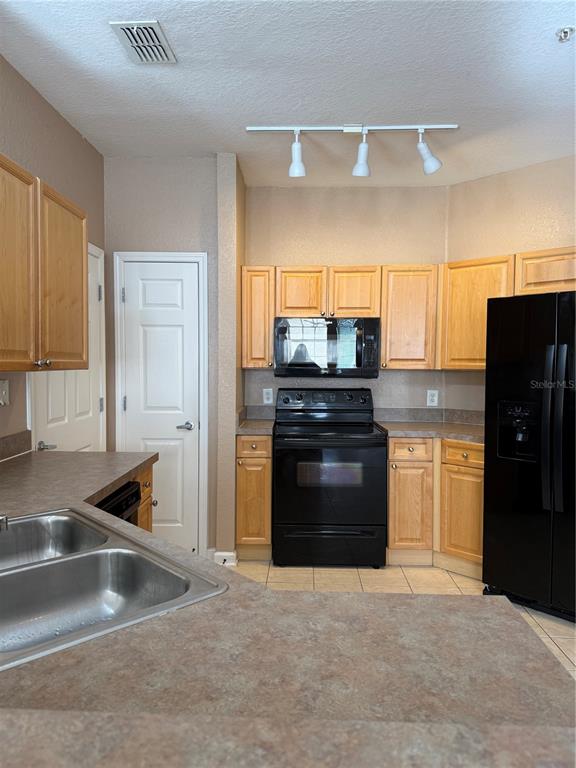 A kitchen features light wood cabinets, black appliances, laminate countertops, and a double sink — 413 TERRACE RIDGE CIRCLE UNIT 413, DAVENPORT, FL