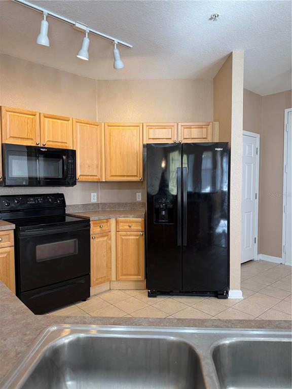 A kitchen features light wood cabinets, black appliances, and a double-basin sink — 413 TERRACE RIDGE CIRCLE UNIT 413, DAVENPORT, FL