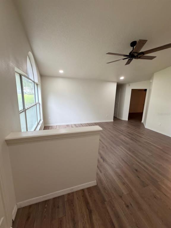 An interior view of a living area with wood-look flooring, a ceiling fan, and windows — 10258 JOANIES RUN, LEESBURG, FL