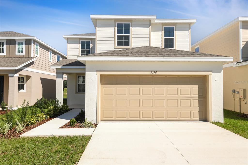 A two-story house with a beige garage, white siding, and a concrete driveway — 6169 SW 64TH STREET, OCALA, FL