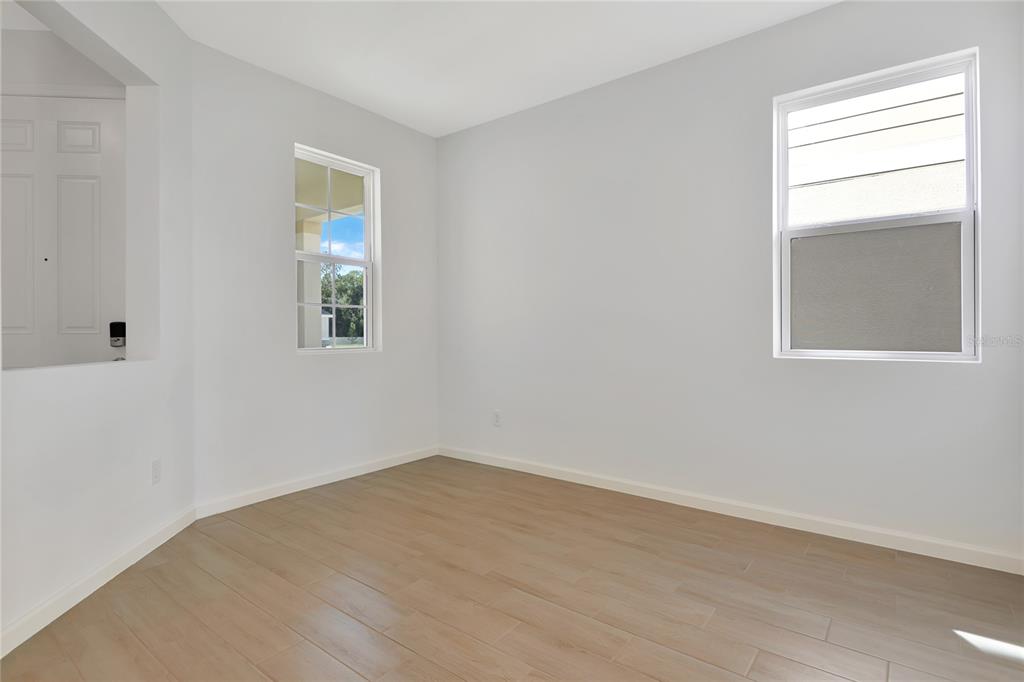 An empty room with light wood-look flooring, white walls, and two windows — 6169 SW 64TH STREET, OCALA, FL