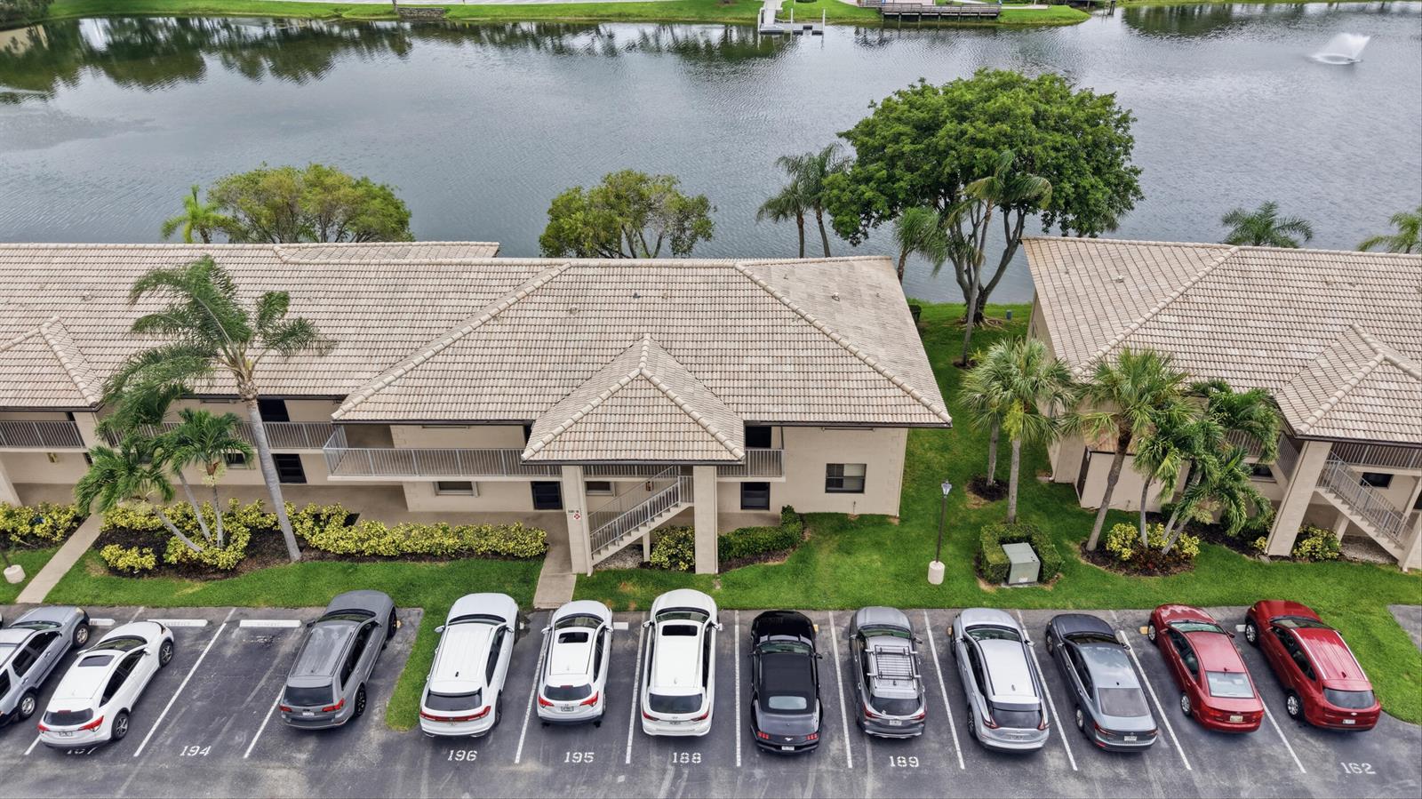 An aerial view shows a two-story apartment building with a tiled roof near a lake — 5501 Lakeside Drive # 207, Margate FL 33063, MARGATE, FL