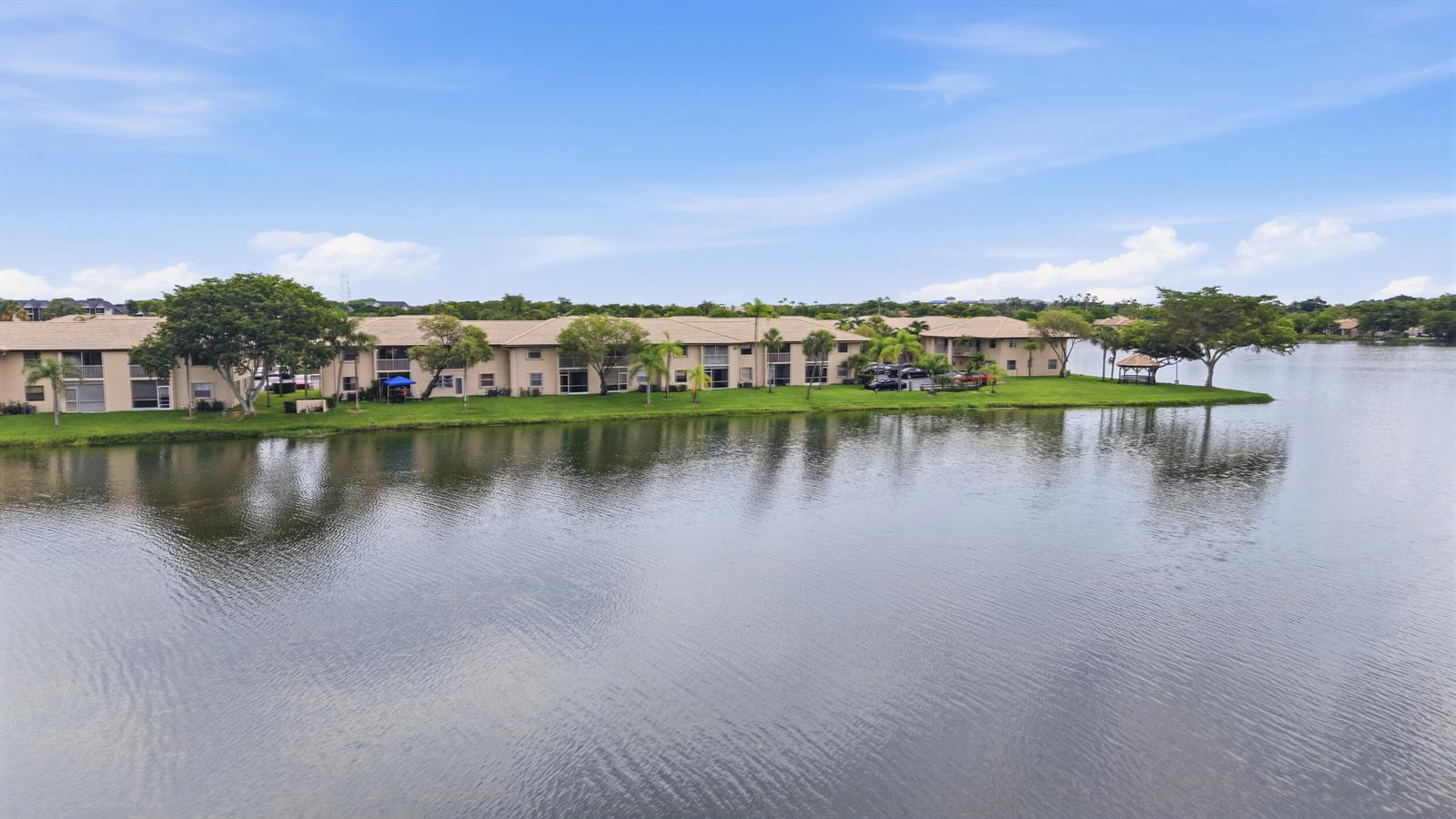 An aerial view of a multi-story apartment complex situated along the edge of a lake — 5501 Lakeside Drive # 207, Margate FL 33063, MARGATE, FL