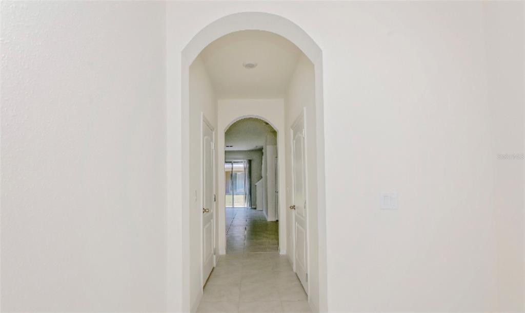 A hallway with arched doorways leads to a tiled room with a sliding glass door — 1280 YELLOW FINCH DRIVE, DAVENPORT, FL