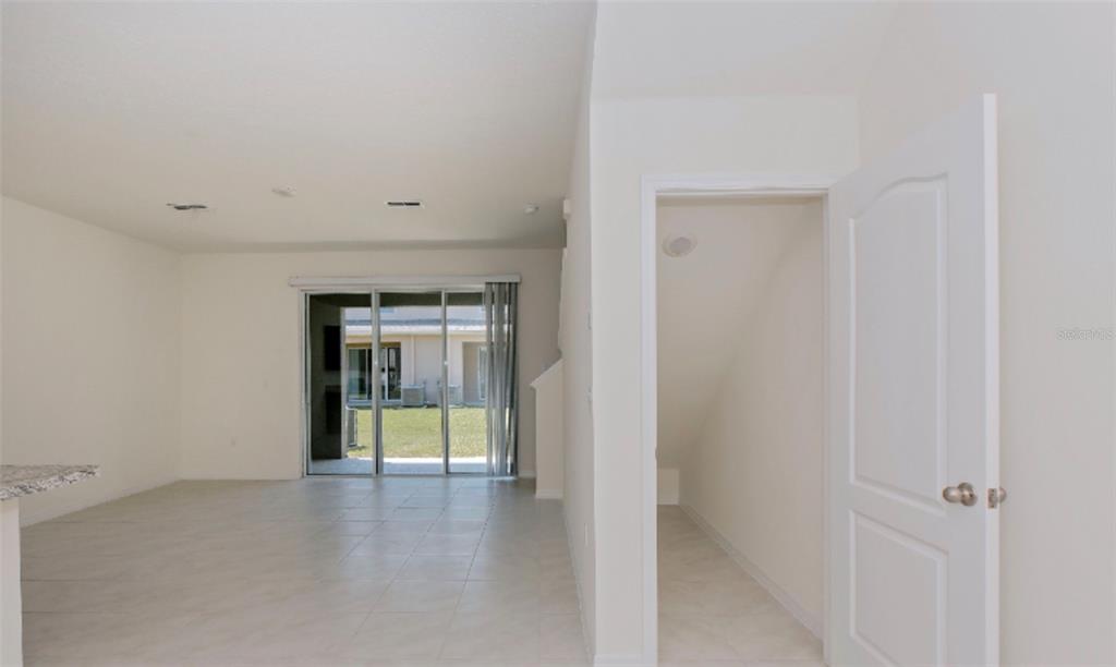 An interior view shows a tiled living area with sliding glass doors and a storage closet — 1280 YELLOW FINCH DRIVE, DAVENPORT, FL