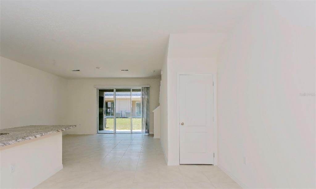 An interior view of a room with tile flooring, a granite countertop, and sliding glass doors — 1280 YELLOW FINCH DRIVE, DAVENPORT, FL