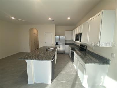 A kitchen features white cabinets, granite countertops, a center island, and stainless steel appliances — 2906 SUNCOAST PLAINS DRIVE, ODESSA, FL
