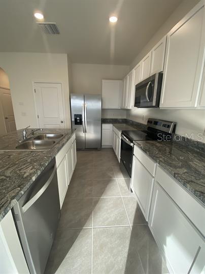 A kitchen with white cabinets, granite countertops, stainless steel appliances, and tile flooring — 2906 SUNCOAST PLAINS DRIVE, ODESSA, FL
