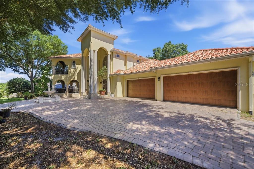 A two-story Mediterranean-style house with a tile roof, arched entry, and three-car garage — 12006 WATERSIDE COURT, TAMPA, FL