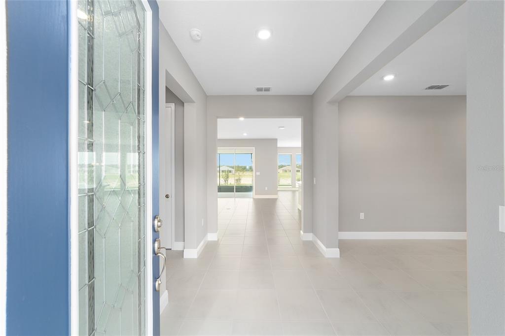 A view from an open front door into a bright, tiled entryway and living area — 10358 SW 105TH COURT, OCALA, FL
