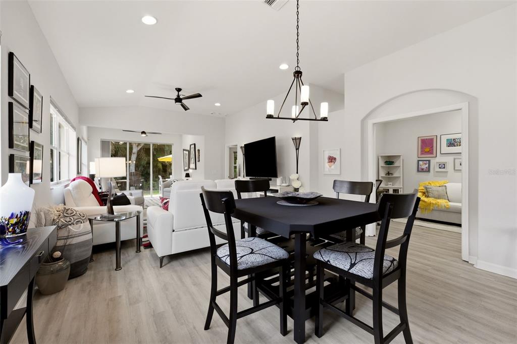 A dining area with a black table and chairs opens into a bright living room — 1071 TOPELIS DRIVE, ENGLEWOOD, FL