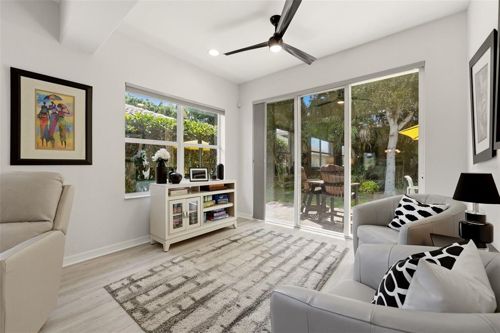 A living room with light flooring, a ceiling fan, sliding glass doors, and two armchairs — 1071 TOPELIS DRIVE, ENGLEWOOD, FL