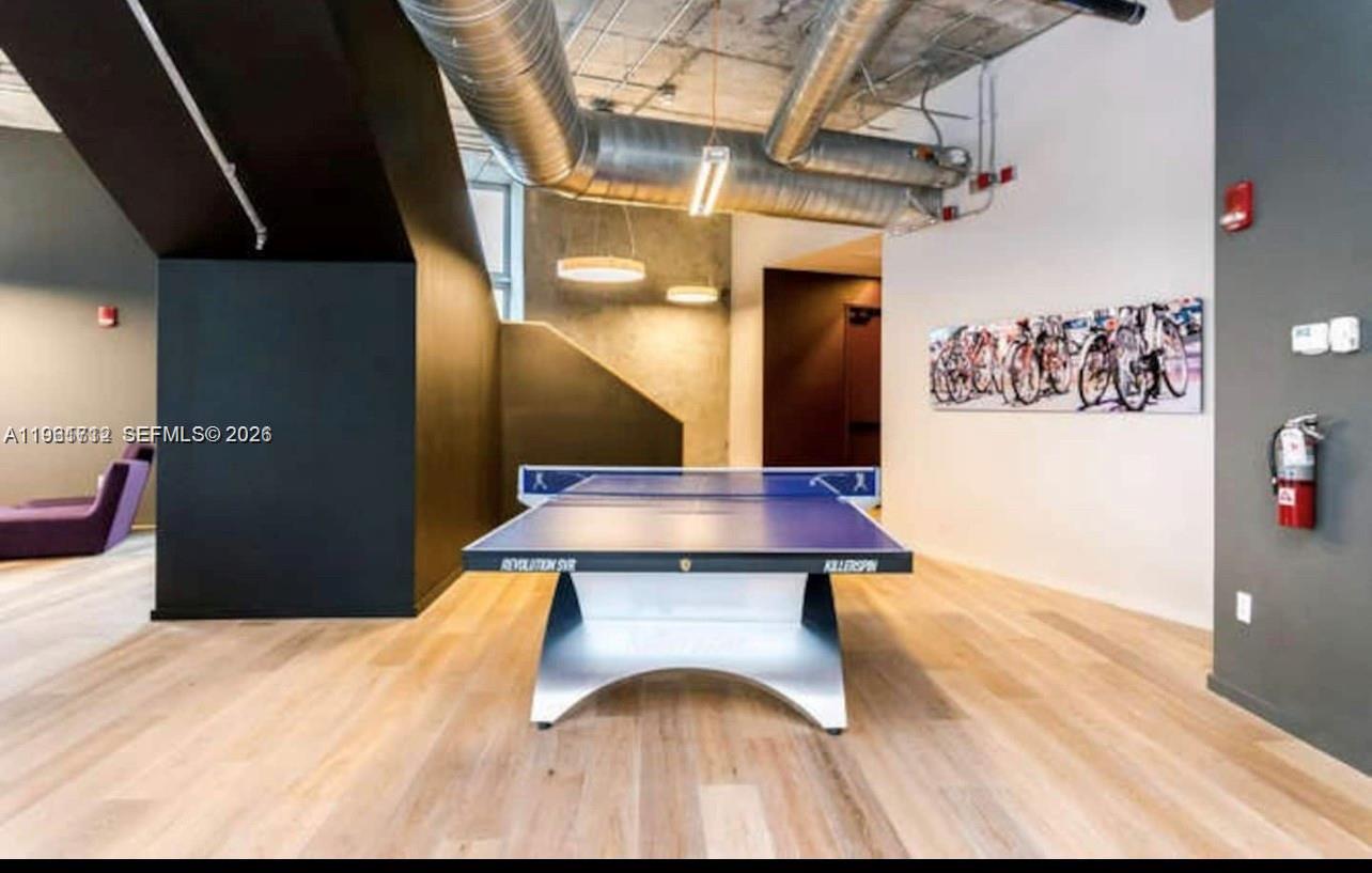 A ping pong table sits in a modern room with exposed ductwork and wood flooring — 151 SE 1st St # 2104, Miami FL 33131, MIAMI, FL