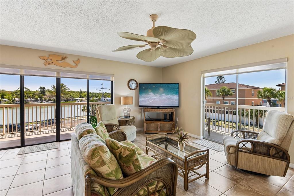 A living room features tile floors, rattan furniture, a ceiling fan, and sliding glass doors — 50 GULF BOULEVARD UNIT 301, INDIAN ROCKS BEACH, FL