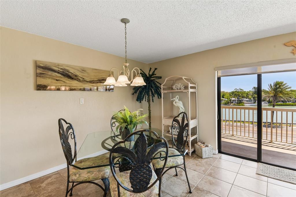 A dining area features a glass table, metal chairs, and a sliding door to a balcony — 50 GULF BOULEVARD UNIT 301, INDIAN ROCKS BEACH, FL