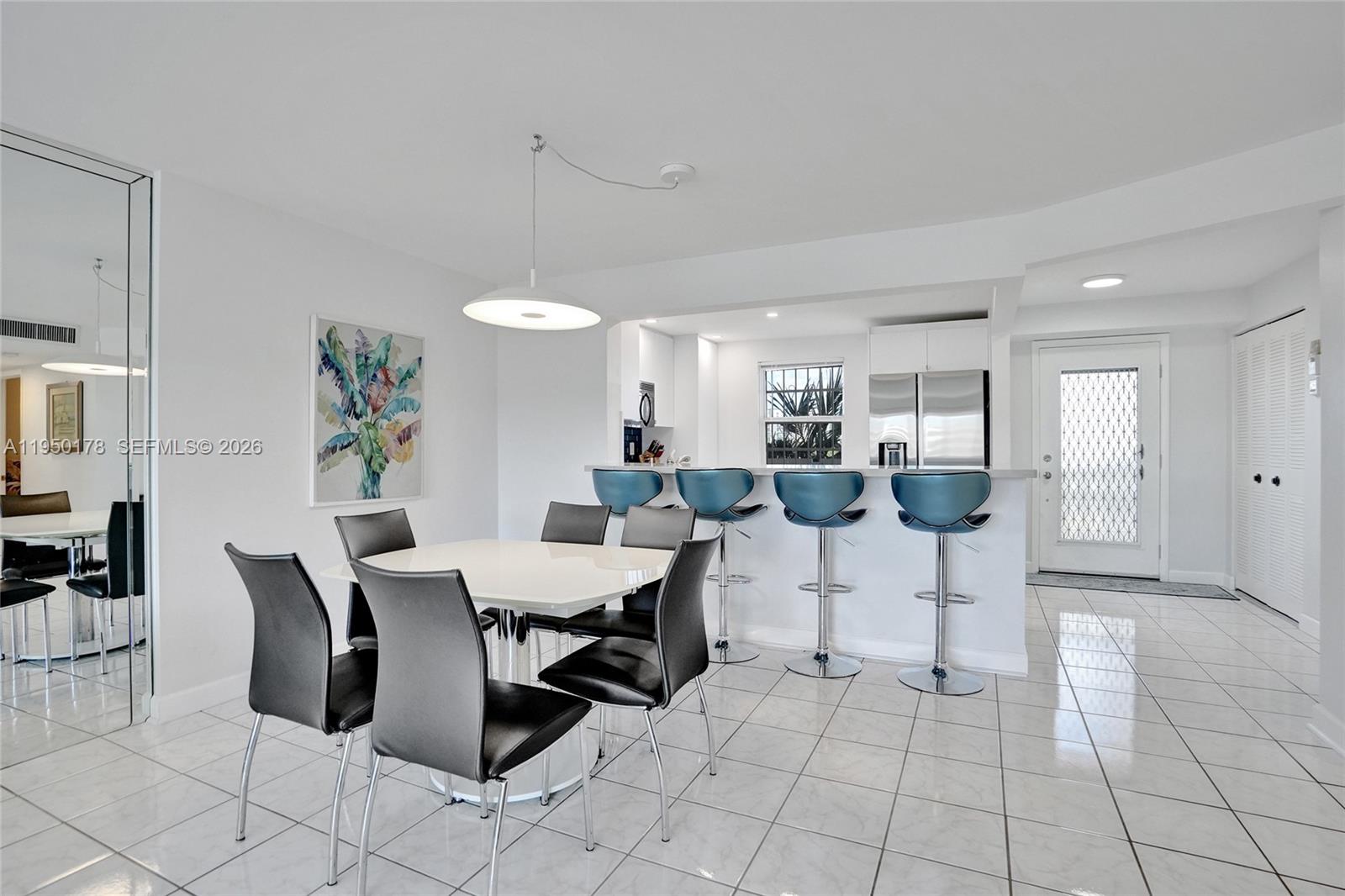 A dining area with a white table and black chairs sits before a kitchen counter — 200 SE 5th Ave # 405, Dania Beach FL 33004, DANIA BEACH, FL