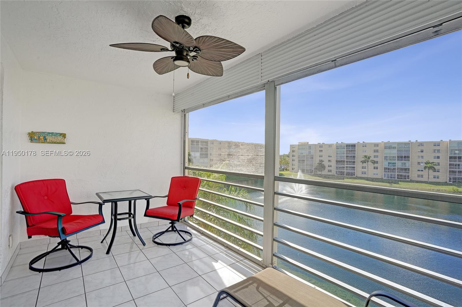 A balcony with red chairs, a small table, a ceiling fan, and a lake view — 200 SE 5th Ave # 405, Dania Beach FL 33004, DANIA BEACH, FL
