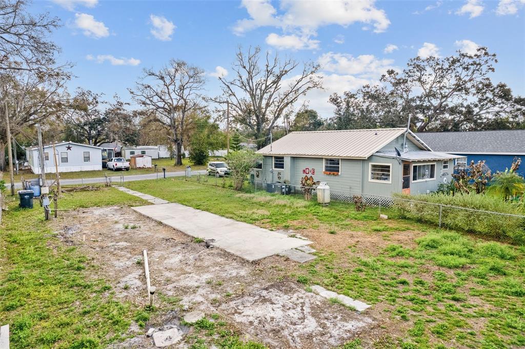 A view of a backyard with a concrete pad, a small house, and a chain-link fence — 12912 CAMBRIDGE AVENUE, TAMPA, FL