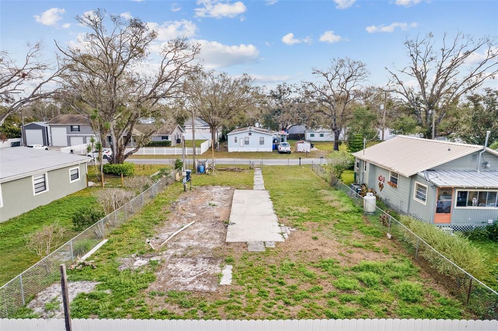 An elevated view shows a fenced, vacant residential lot with a central concrete slab — 12912 CAMBRIDGE AVENUE, TAMPA, FL