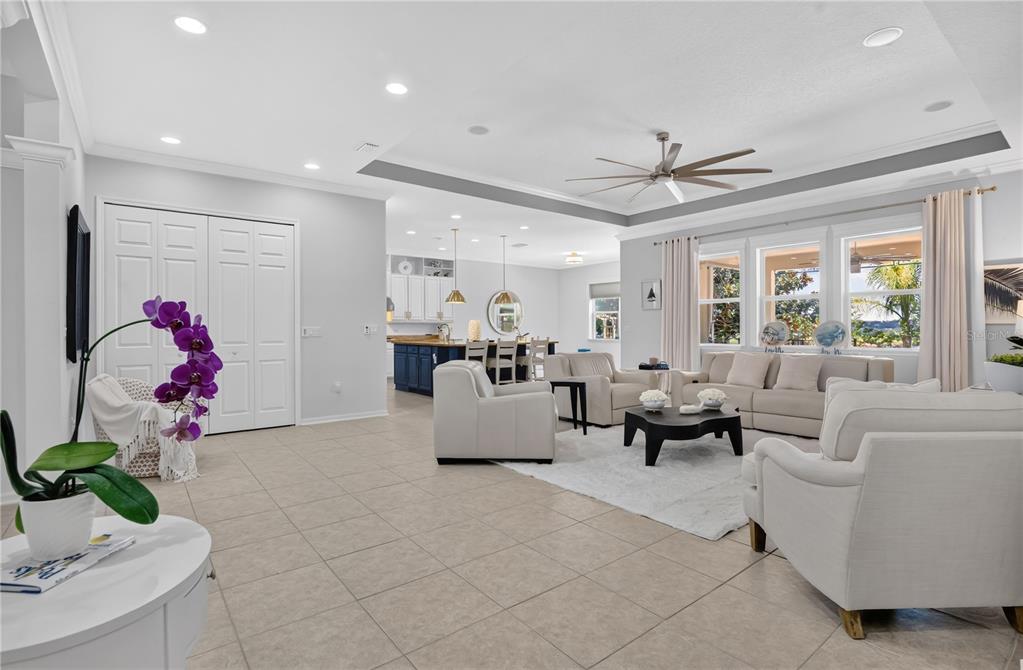 A spacious open-concept living room with tile floors, neutral furniture, and a kitchen in back — 1744 BELLA LAGO DRIVE, CLERMONT, FL