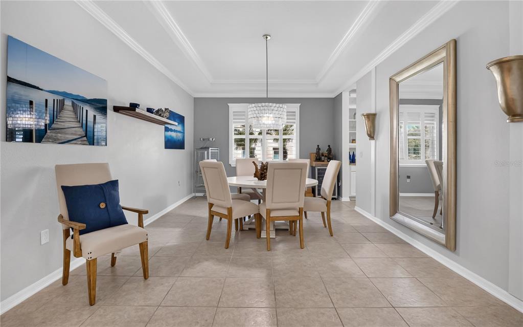 A dining room features a round table, upholstered chairs, a chandelier, and a large mirror — 1744 BELLA LAGO DRIVE, CLERMONT, FL