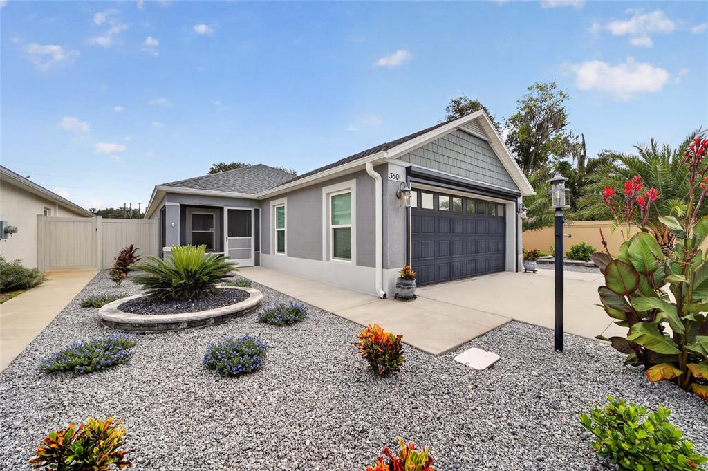 A single-story house with a gray exterior, a two-car garage, and a gravel front yard — 3501 CONNOR WAY, THE VILLAGES, FL