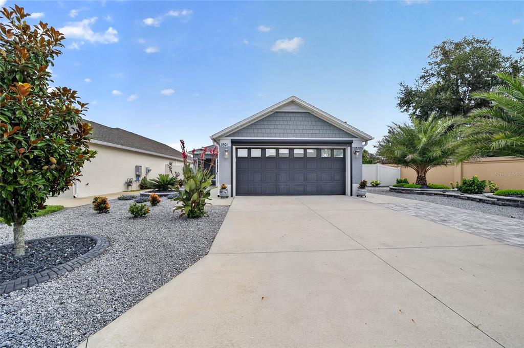 A single-story house with a gray garage door, a concrete driveway, and landscaped gravel beds — 3501 CONNOR WAY, THE VILLAGES, FL