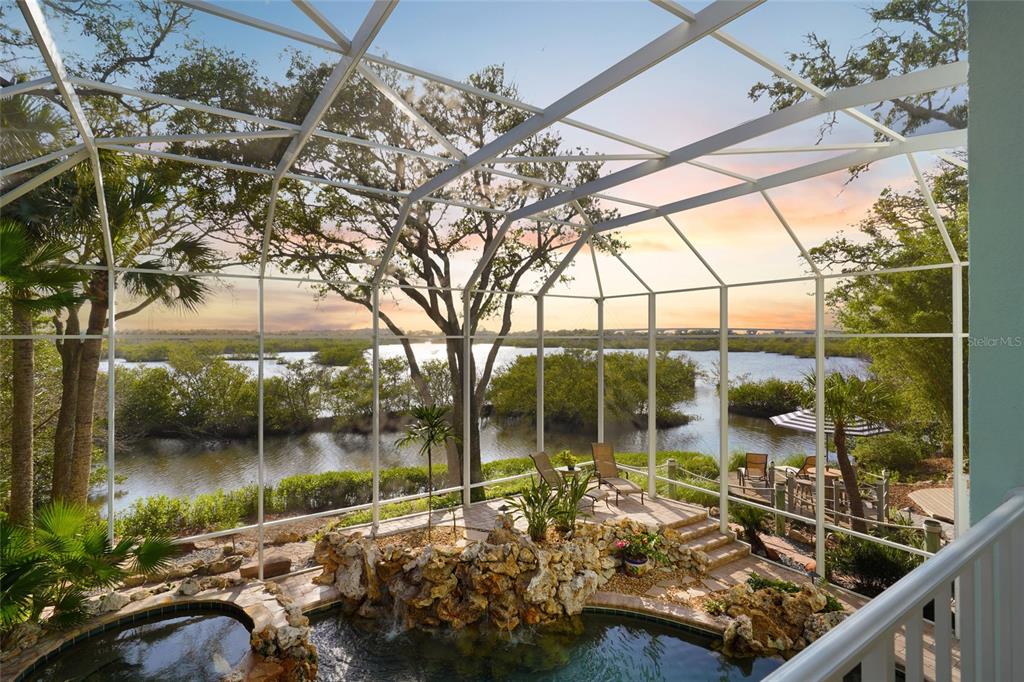 A screened-in patio features a rock waterfall, a pool, and views of a river — 1004 S FLAGLER AVENUE, FLAGLER BEACH, FL