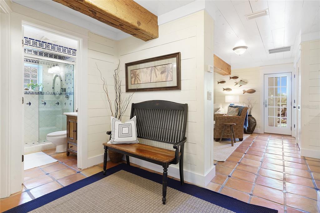 An entryway features a wooden bench, shiplap walls, exposed ceiling beams, and terracotta tile flooring — 1004 S FLAGLER AVENUE, FLAGLER BEACH, FL