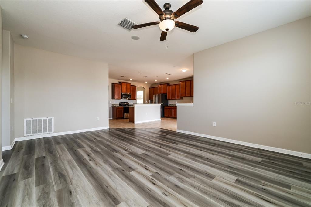 A living room with wood-look flooring opens to a kitchen with dark wood cabinets — 2320 DOVESONG TRACE DRIVE, RUSKIN, FL