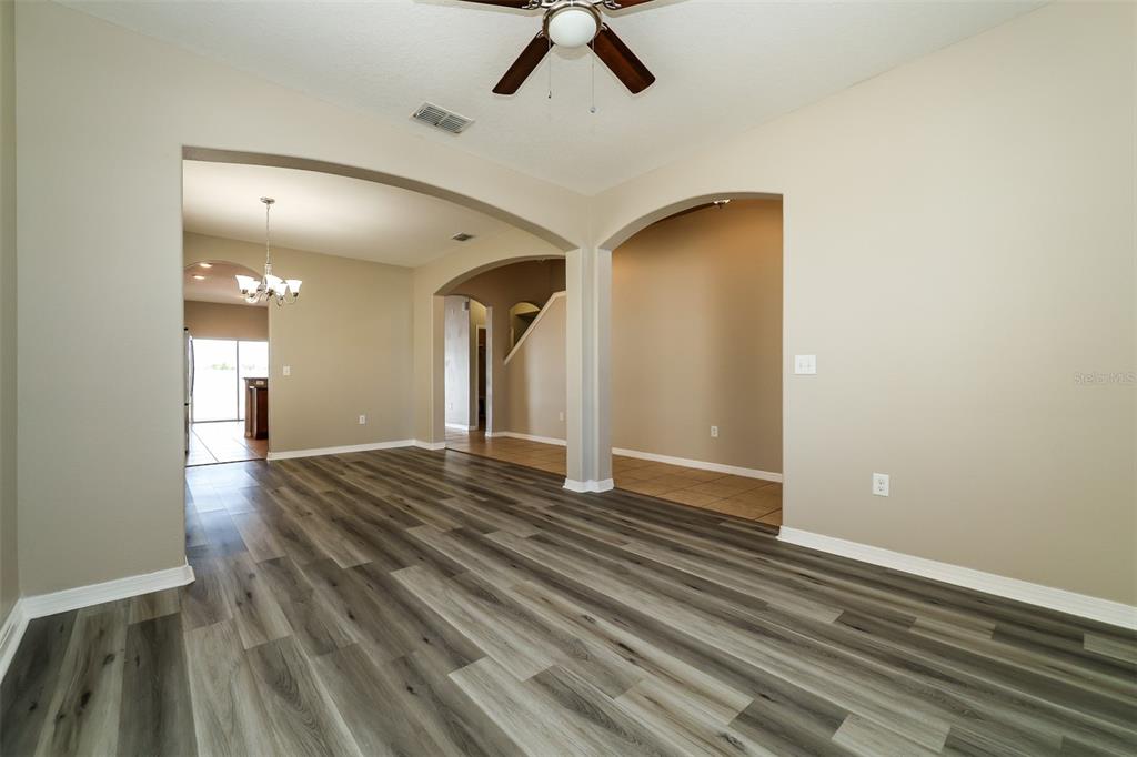 An interior view of a room with wood-look flooring, arched doorways, and a ceiling fan — 2320 DOVESONG TRACE DRIVE, RUSKIN, FL