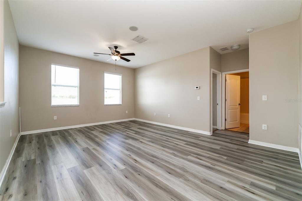 An empty room features light-colored walls, a ceiling fan, and wood-look vinyl plank flooring — 2320 DOVESONG TRACE DRIVE, RUSKIN, FL