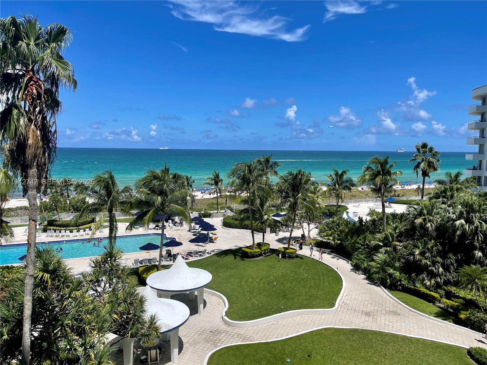An elevated view of a resort pool area, lush landscaping, and a sandy beach — 5161 Collins Ave # 715, Miami Beach FL 33140, MIAMI BEACH, FL