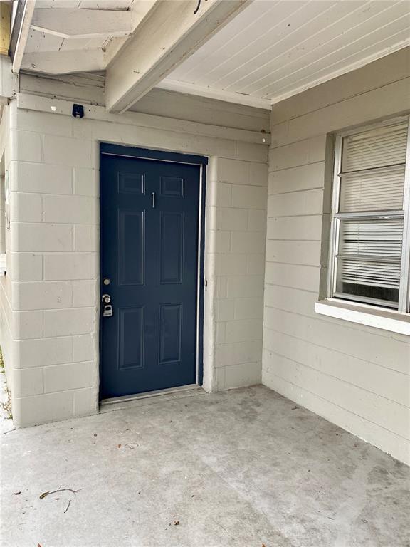 A blue front door with the number one is set into a gray concrete block wall — 38313 TUCKER ROAD, ZEPHYRHILLS, FL