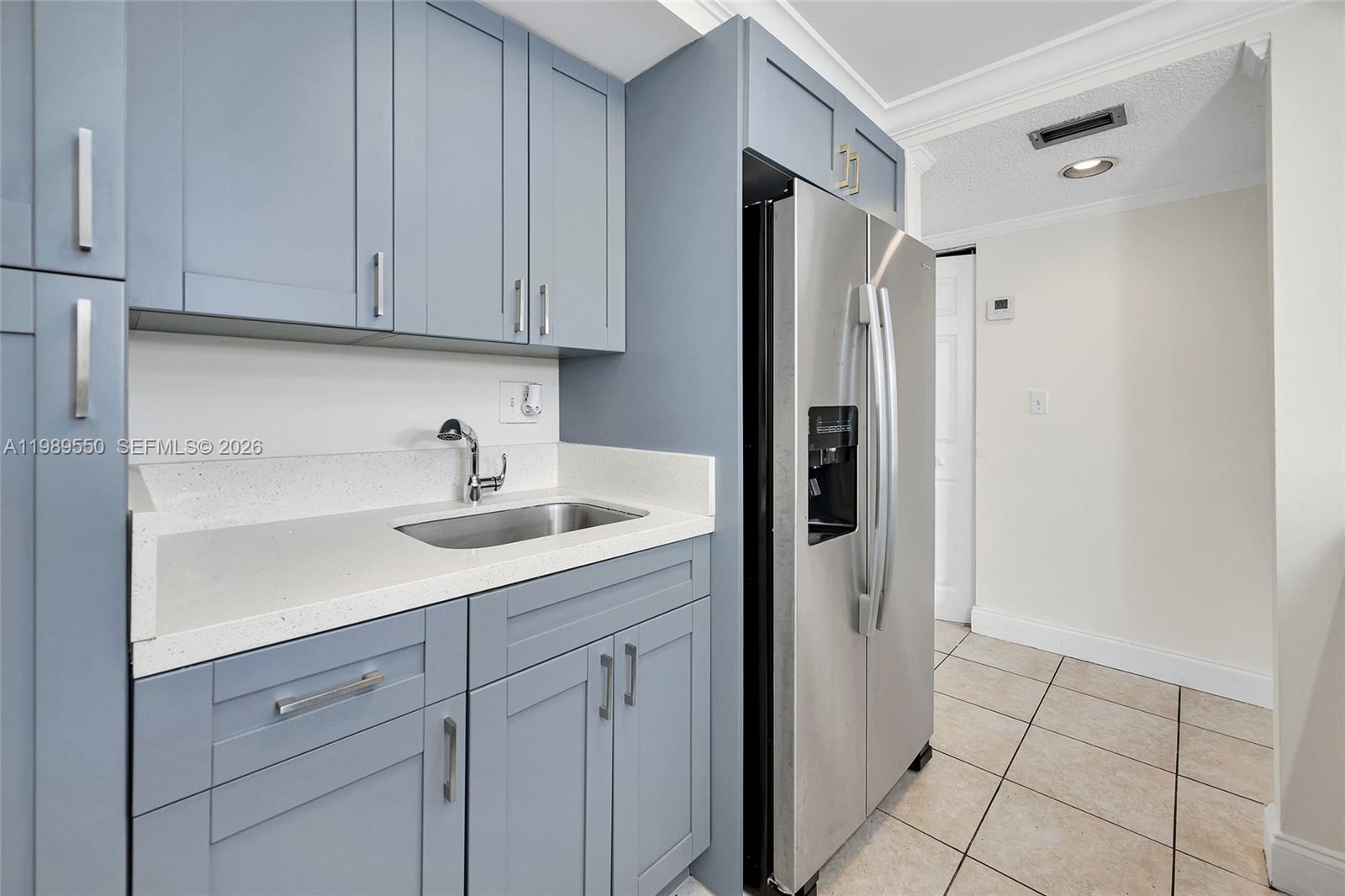A kitchen area features blue cabinets, a stainless steel refrigerator, and a white countertop — 14601 N Kendall Dr # 308K, Miami FL 33186, MIAMI, FL