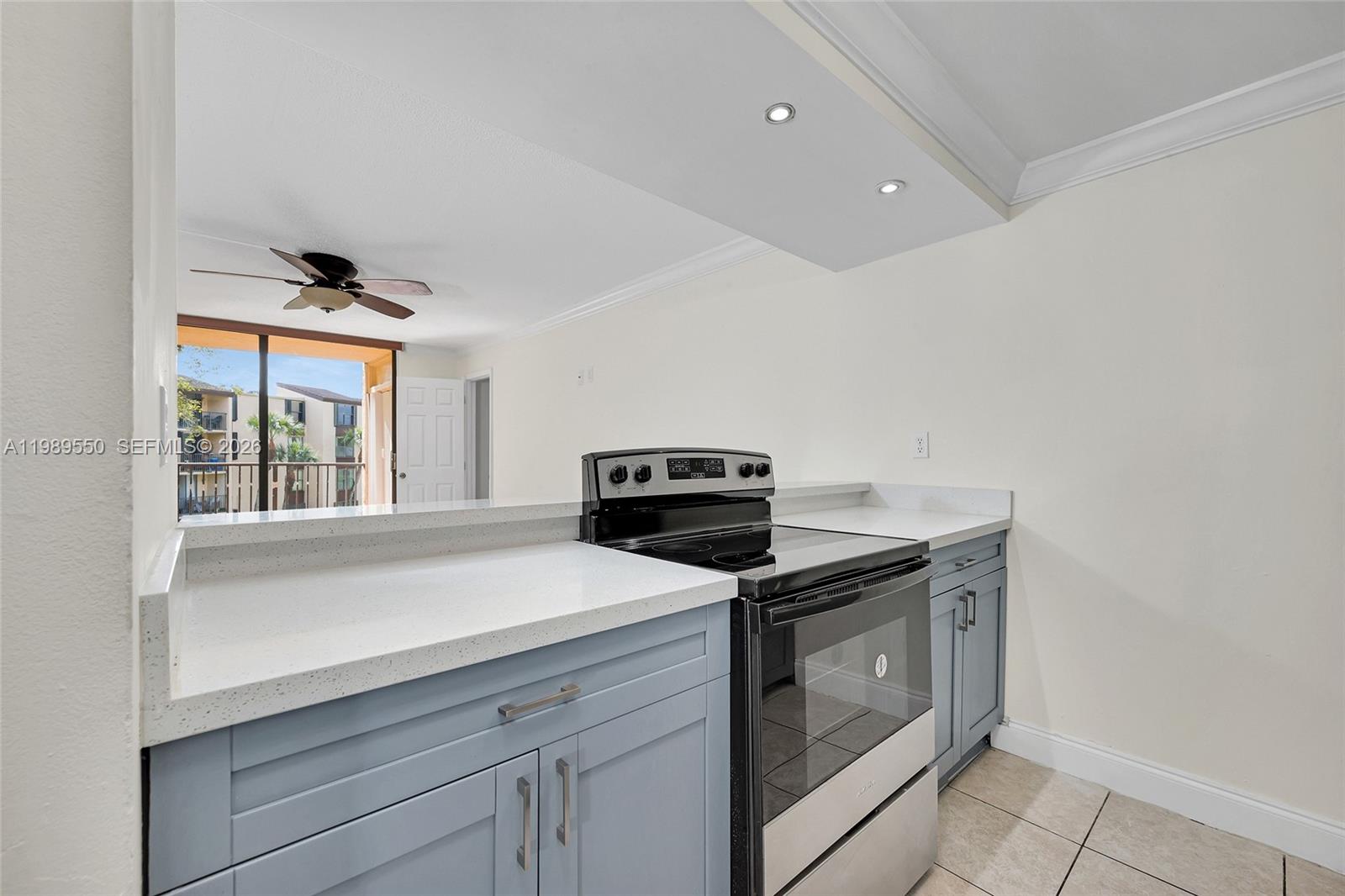 A kitchen features light blue cabinets, white countertops, and a black stove — 14601 N Kendall Dr # 308K, Miami FL 33186, MIAMI, FL