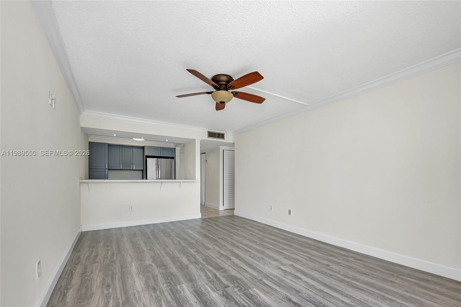 A living room features light-colored walls, wood-look flooring, a ceiling fan, and a kitchen pass-through — 14601 N Kendall Dr # 308K, Miami FL 33186, MIAMI, FL