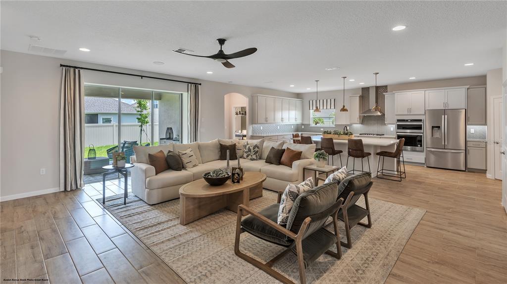 An open-concept living room and kitchen feature light wood-look tile floors and neutral furniture — 3547 CYNTHIA LANE, ORANGE PARK, FL