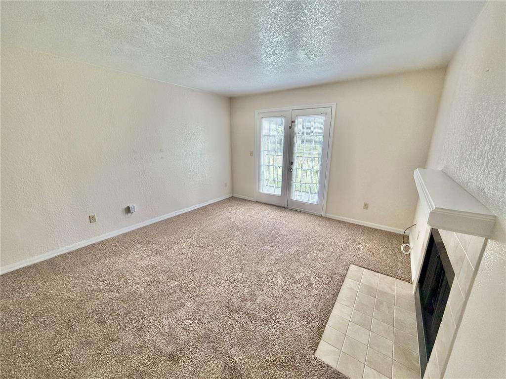 A carpeted living room features a fireplace with a white mantel and glass French doors — 2550 N ALAFAYA TRAIL UNIT 5105, ORLANDO, FL