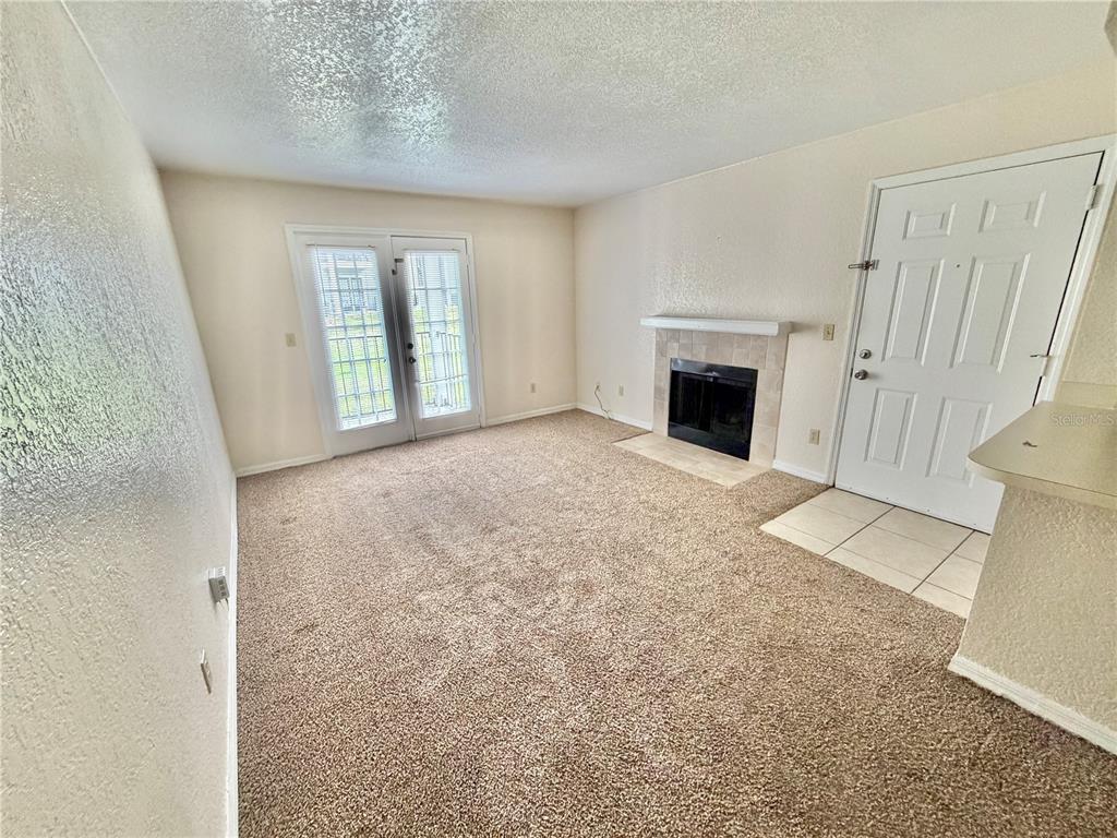 A living room with beige carpet, a fireplace, and glass doors leading to the outside — 2550 N ALAFAYA TRAIL UNIT 5105, ORLANDO, FL
