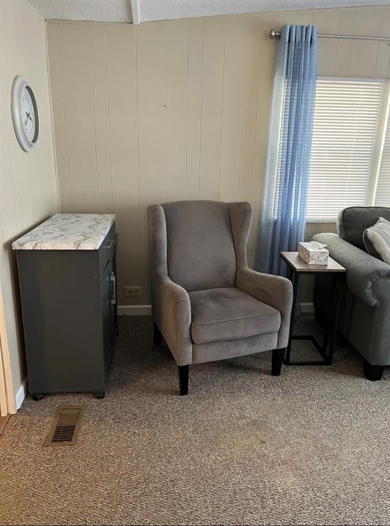 A living room features a grey wingback chair, a small cabinet, and a side table — 38961 STAPLEY CIRCLE, ZEPHYRHILLS, FL