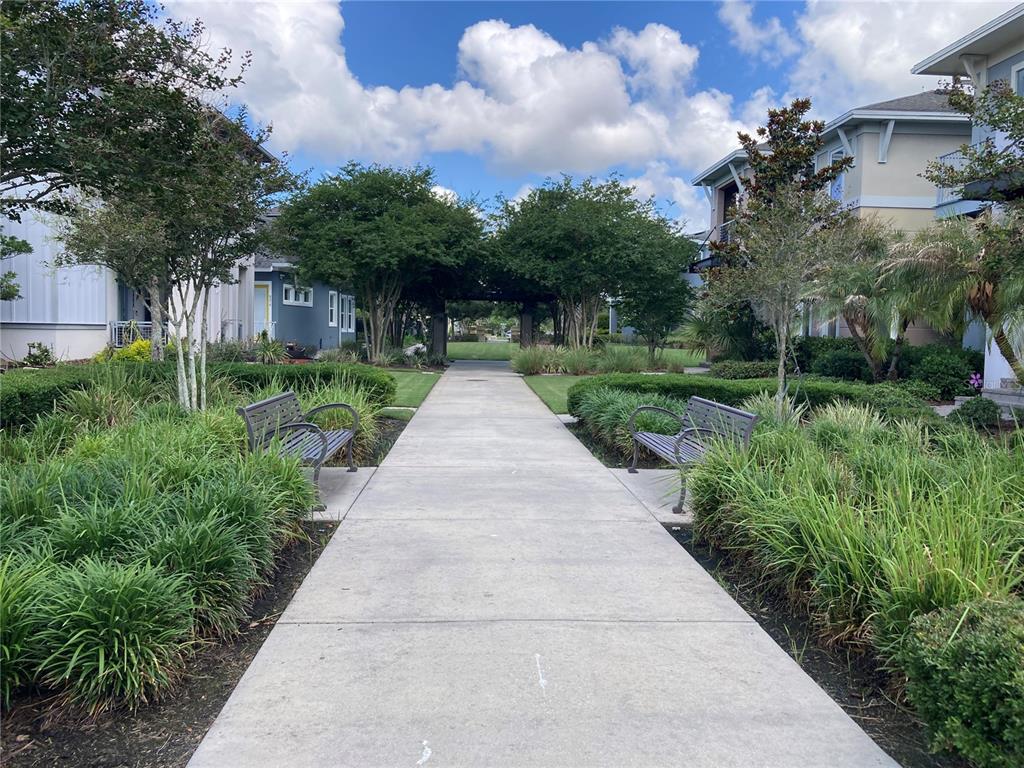 A concrete walkway leads between two apartment buildings with benches and landscaping on both sides — 8461 GREIDER WAY, ORLANDO, FL