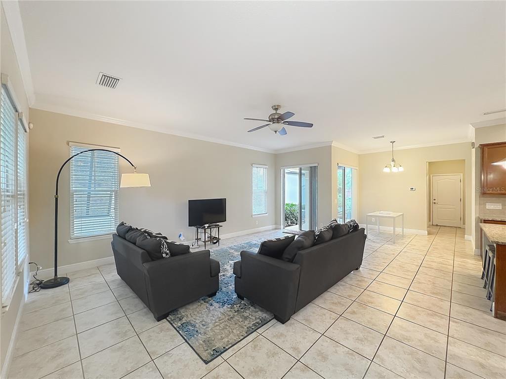 A living room with tile floors, two dark sofas, a television, and a ceiling fan — 8461 GREIDER WAY, ORLANDO, FL