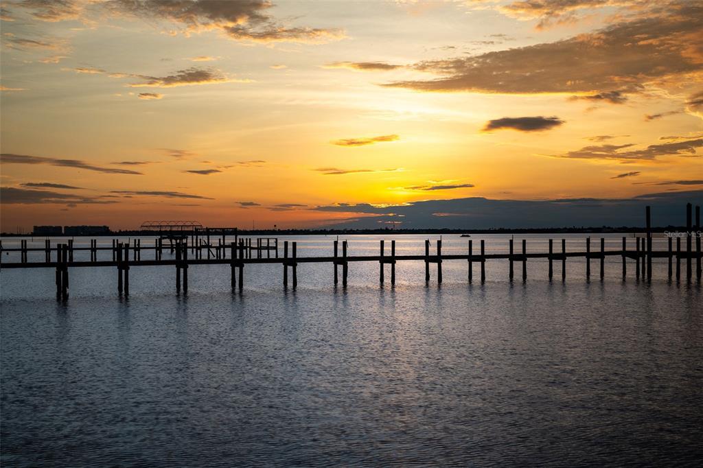 A long wooden pier extends into a calm body of water during a golden sunset — 25472 SHORE DRIVE, PUNTA GORDA, FL
